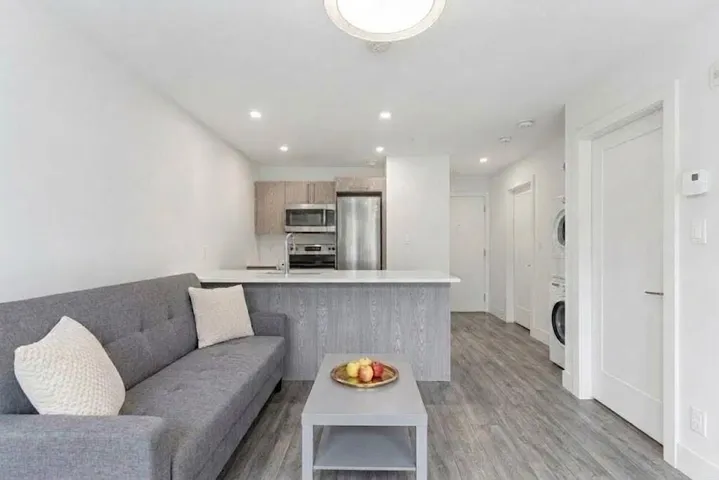 Open-concept living area featuring wood-finish flooring, recessed lighting, and a kitchen with stainless steel appliances
