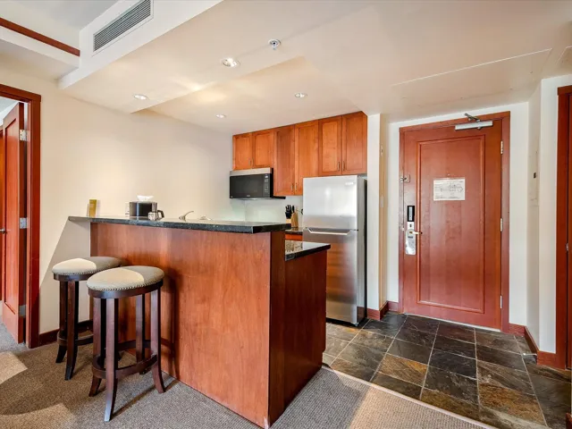 Kitchen featuring visible vents, baseboards, dark countertops, freestanding refrigerator, and a peninsula