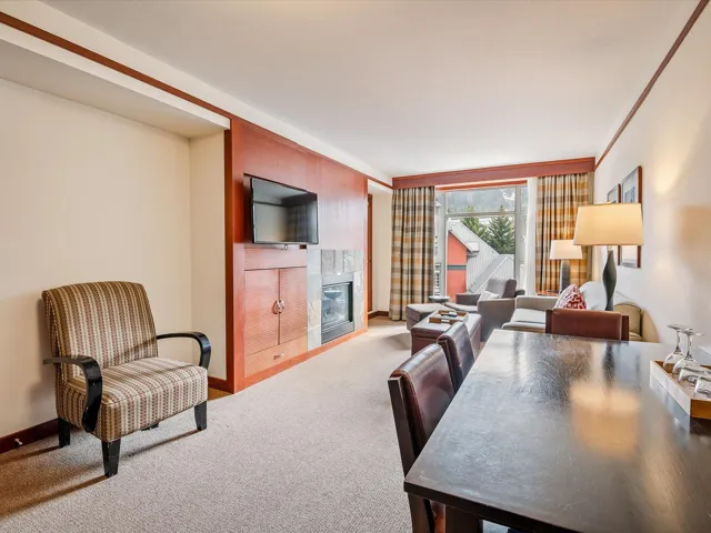 Carpeted living area with a tile fireplace and baseboards