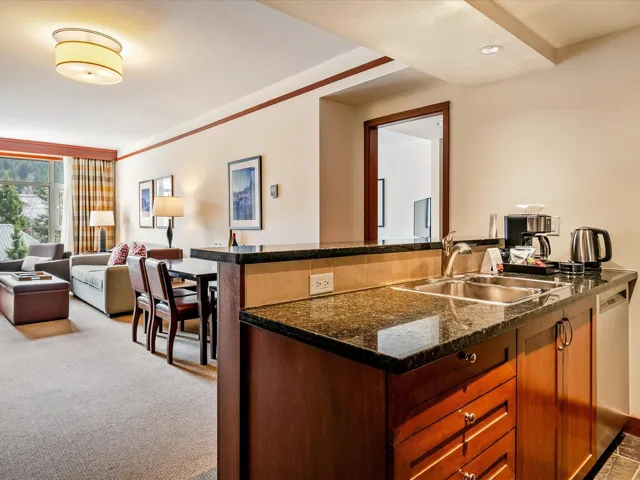 Kitchen featuring open floor plan, carpet floors, dark stone counters, dishwasher, and a sink