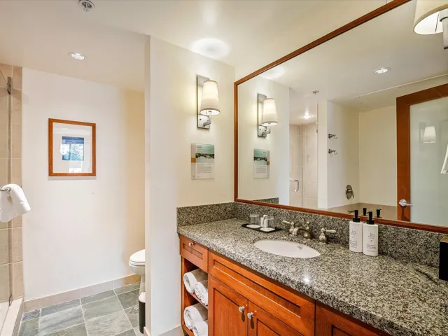 Full bath with vanity, toilet, a stall shower, baseboards, and stone tile flooring