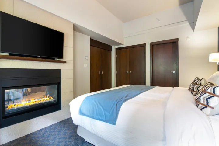 Bedroom featuring multiple closets, a multi sided fireplace, and dark colored carpet