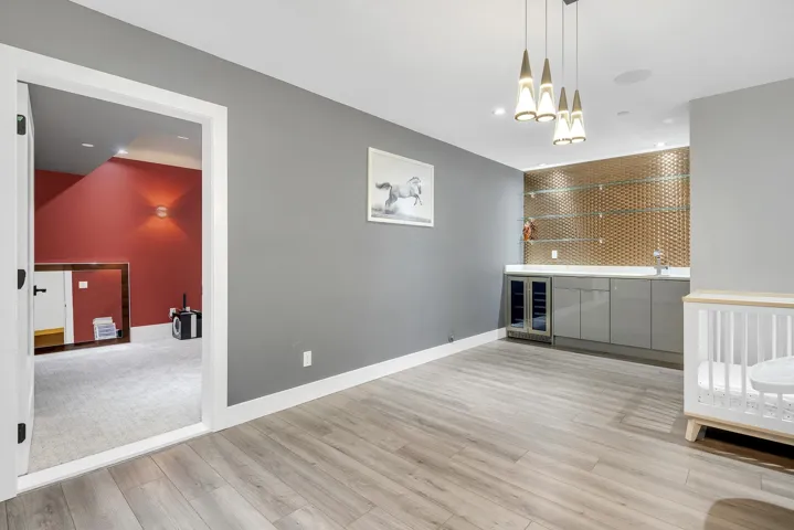 Unfurnished living room featuring bar area, light wood-type flooring, wine cooler, recessed lighting, and a chandelier