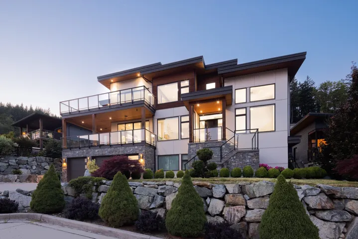 Contemporary house with a balcony, stone siding, stucco siding, an attached garage, and stairway
