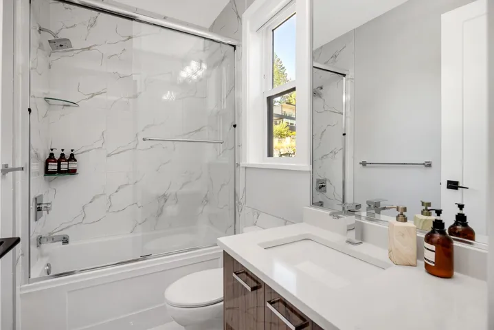 Bathroom featuring vanity and shower / bath combination with glass door