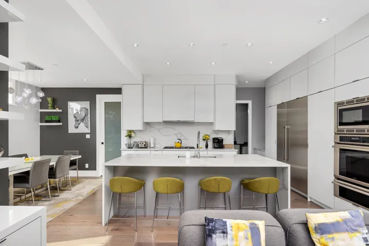 Kitchen featuring modern cabinets, light wood-style floors, a kitchen breakfast bar, white cabinets, and recessed lighting