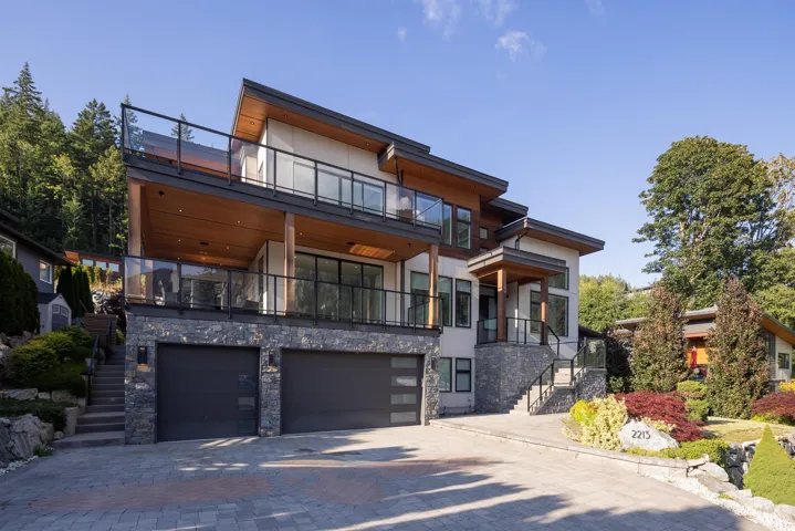 Contemporary home featuring stairs, a balcony, stone siding, decorative driveway, and an attached garage