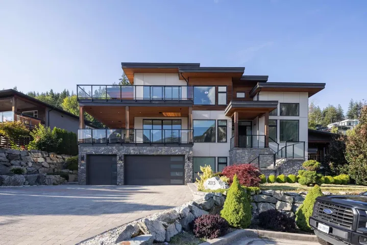 Modern home featuring stucco siding, stone siding, decorative driveway, a garage, and a balcony