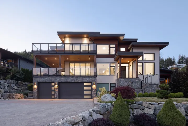 Modern home featuring a balcony, stone siding, an attached garage, stucco siding, and decorative driveway
