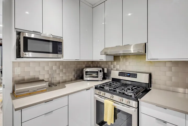 Kitchen featuring appliances with stainless steel finishes, white cabinetry, and range hood