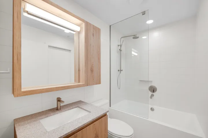 Modern bathroom featuring a wood-finish vanity with an integrated sink and speckle-patterned countertop