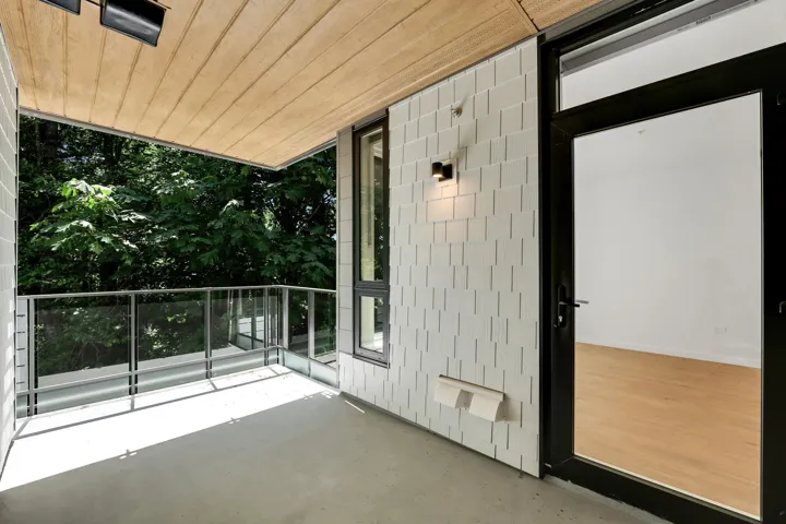Private balcony with a concrete floor, glass railing, and a wood-paneled ceiling