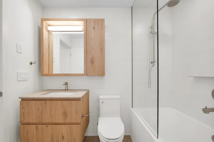 Modern bathroom featuring a wood-finish vanity with an integrated sink and light-toned countertop