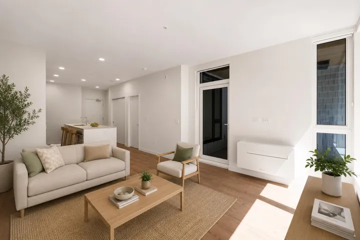 Open-concept living area featuring wood-finish flooring, recessed lighting, and a white kitchen island with a sink and breakfast bar
