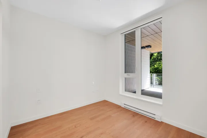 Bright room featuring wood-finish flooring, white walls, and a large window