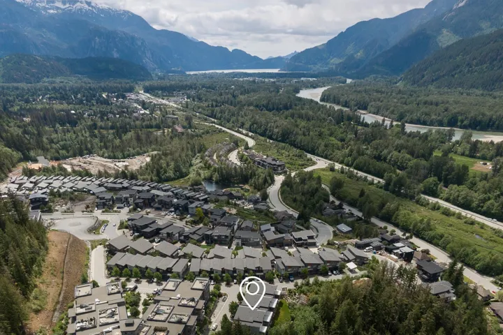 Aerial overview of property's location with a forest, a mountain backdrop, and nearby suburban area