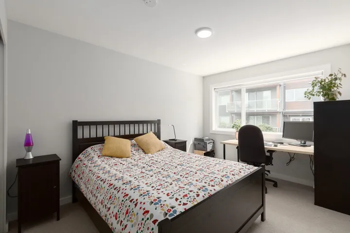 Bedroom with light carpet, an office area, and baseboards