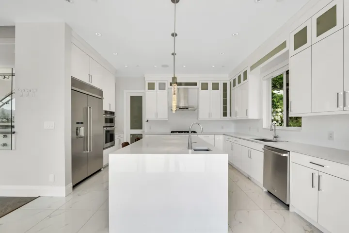 Gourmet kitchen featuring a large central island, white cabinetry, stainless steel appliances, and recessed lighting