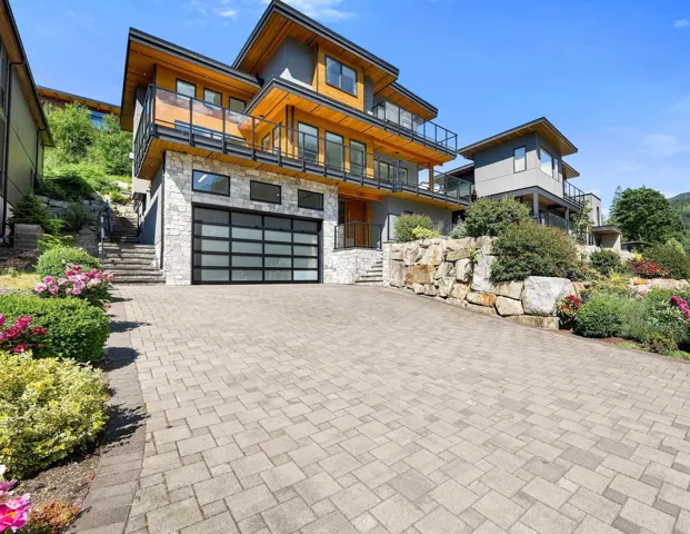 Contemporary multi-level residence featuring a stone veneer facade and natural wood-look siding