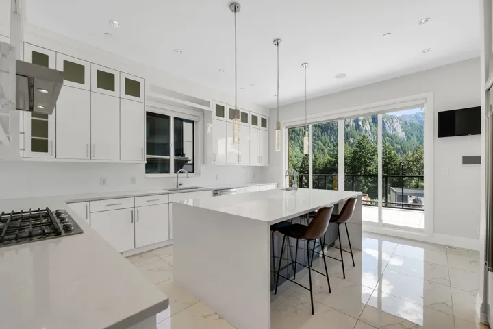 Modern kitchen featuring a large center island, white cabinetry, integrated stainless steel appliances, and a gas cooktop