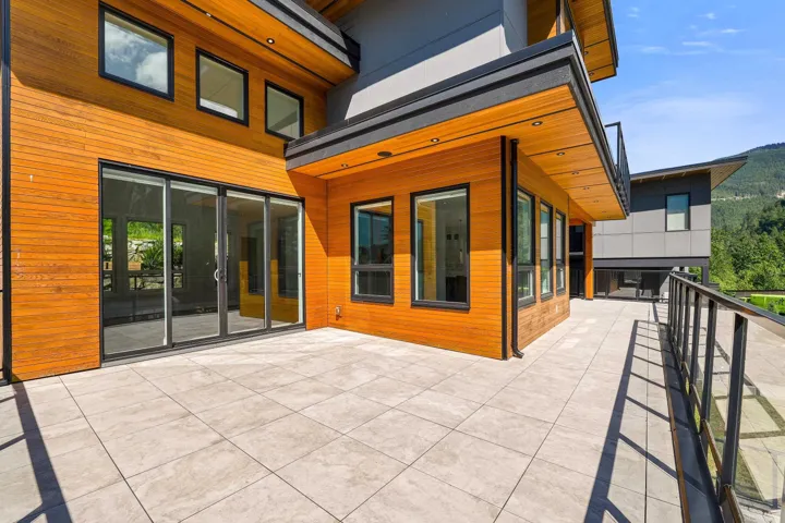 Spacious outdoor patio featuring large format tile flooring and a glass panel railing