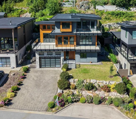 Contemporary multi-level residence featuring a flat roofline, an integrated two-car garage with a frosted panel door, and multiple balconies with glass railings