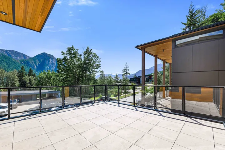 Expansive outdoor patio featuring light-colored square tile flooring and clear glass railings