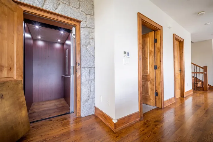 In-home elevator featuring wood-finish flooring and recessed lighting