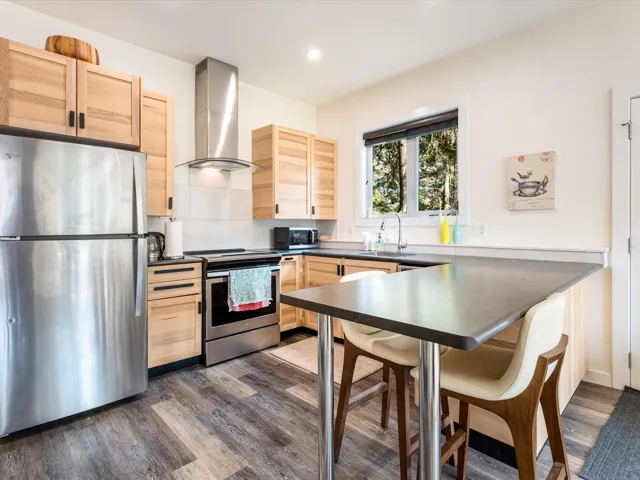 Kitchen with light brown cabinets, stainless steel appliances, a peninsula, dark wood finished floors, and recessed lighting