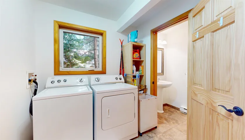 Dedicated laundry area featuring a wood-trimmed window, white appliances, and tiled flooring