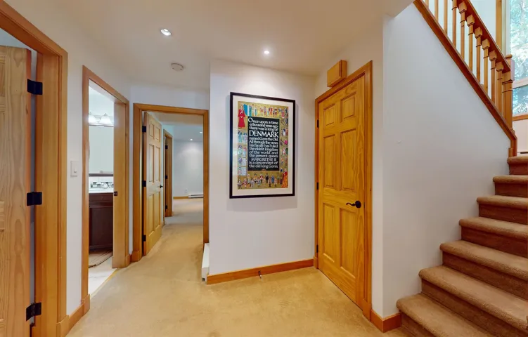 Carpeted hallway featuring multiple wood-paneled doors, recessed lighting, and wood trim accents