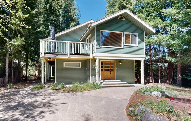 Two-story property featuring green horizontal siding and a large upper-level balcony with white railings