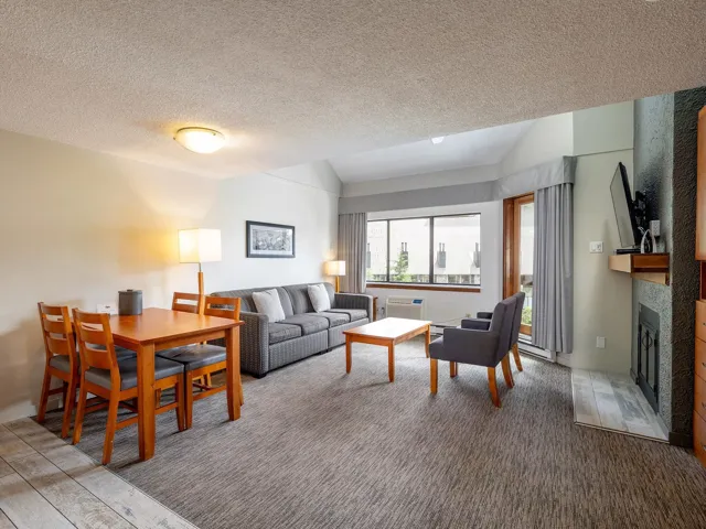 Carpeted living room featuring lofted ceiling, a fireplace, a textured ceiling, and a wall unit AC