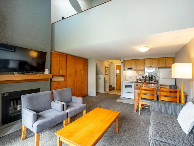 Carpeted living room featuring a glass covered fireplace and stairway