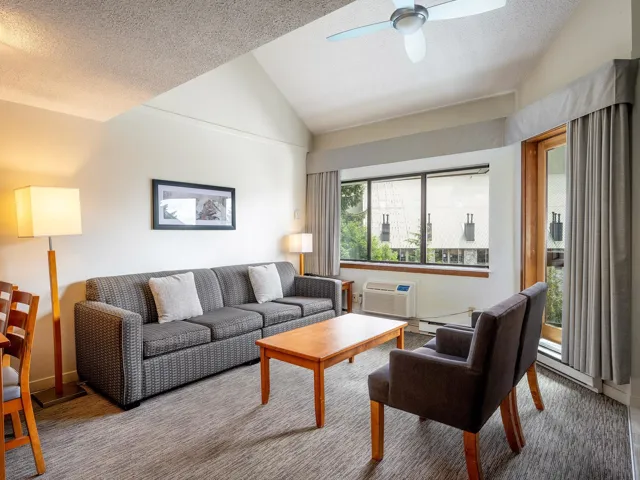 Living room featuring vaulted ceiling, a ceiling fan, a textured ceiling, baseboard heating, and carpet floors