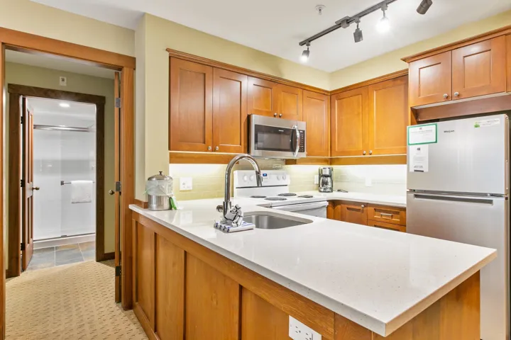 Kitchen featuring appliances with stainless steel finishes, brown cabinets, and light stone countertops