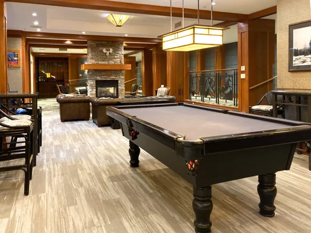 Recreation room with a fireplace, billiards, beamed ceiling, wooden walls, and light wood-style floors
