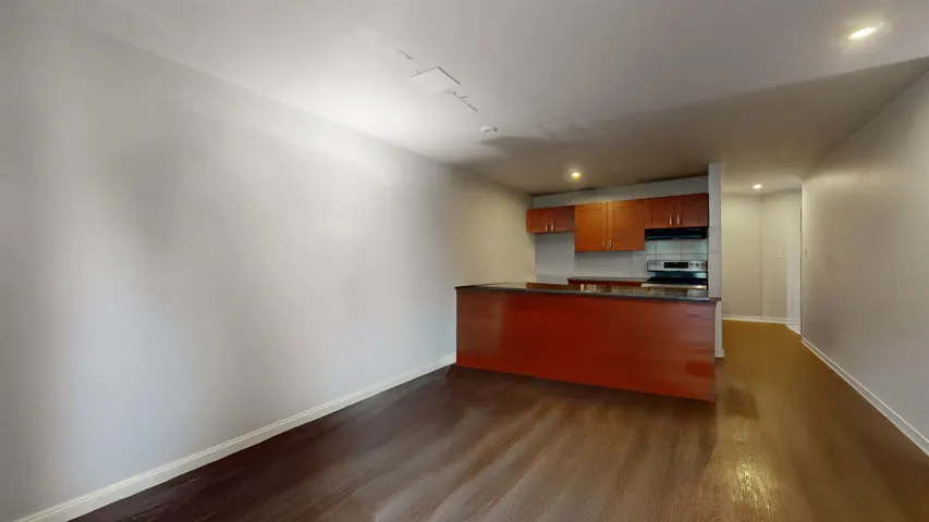 Kitchen featuring stainless steel range with electric stovetop, dark countertops, dark wood-type flooring, recessed lighting, and under cabinet range hood