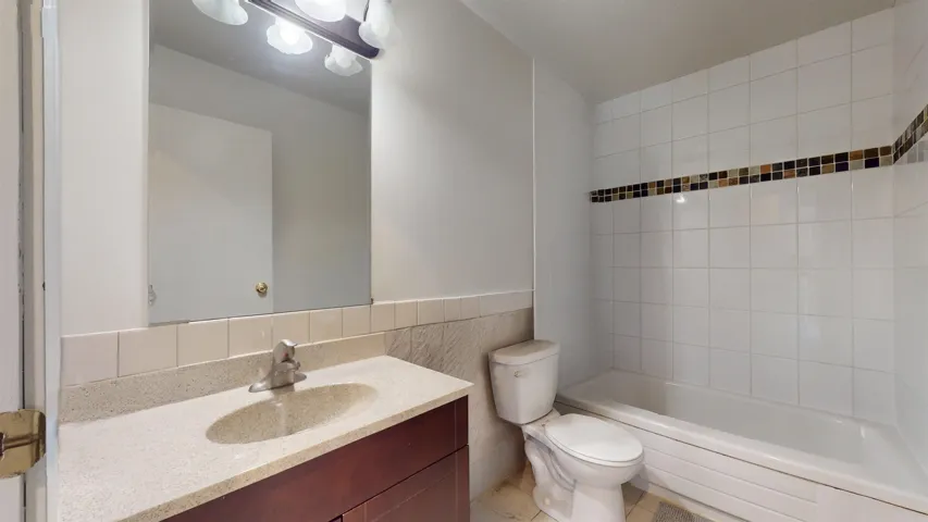 Full bath with vanity, bathing tub / shower combination, and tile walls