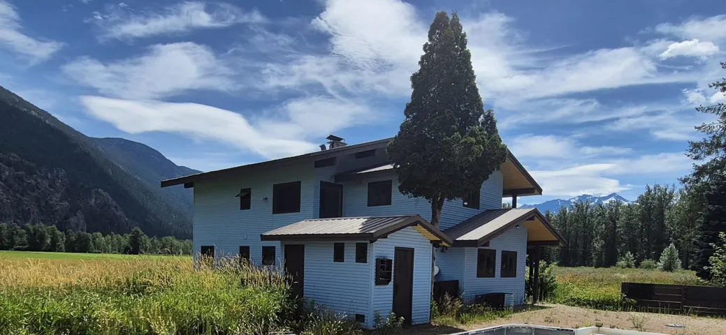 Back of house with a mountain view, a metal roof, and a forest view