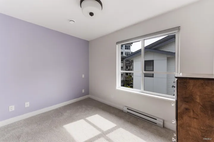 Carpeted empty room with a baseboard heating unit and baseboards