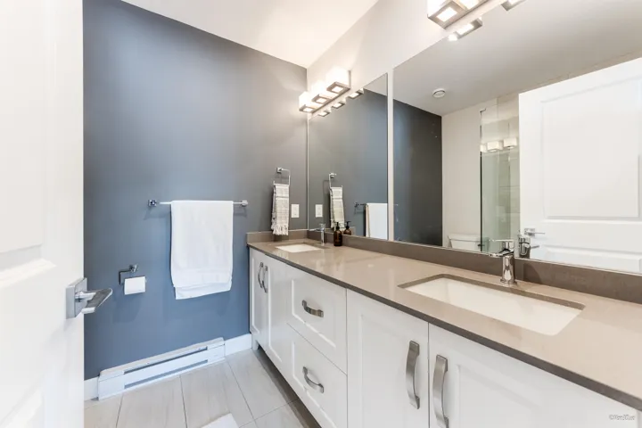 Full bathroom with a baseboard radiator, double vanity, tile patterned flooring, and an enclosed shower