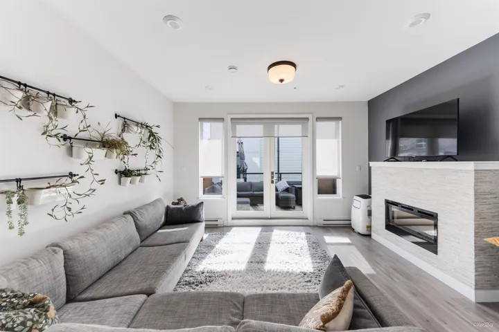 Living room featuring wood finished floors, a glass covered fireplace, french doors, and a baseboard heating unit