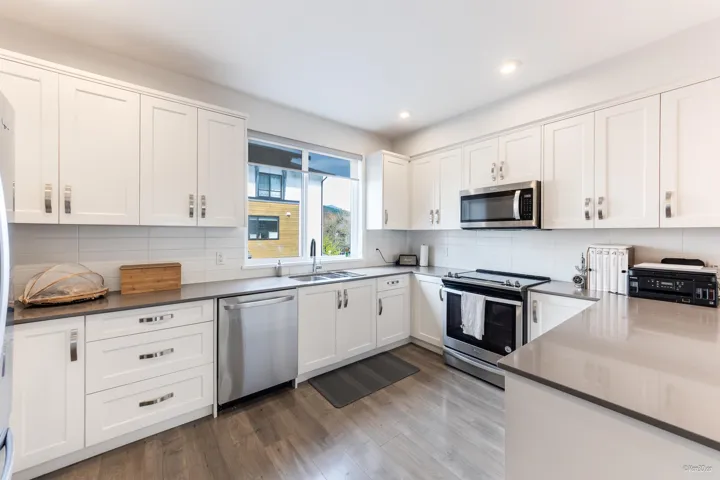 Kitchen with stainless steel appliances, white cabinets, recessed lighting, wood finished floors, and decorative backsplash