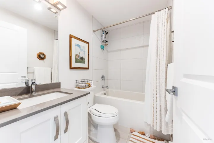 Bathroom featuring vanity and shower / bathtub combination with curtain