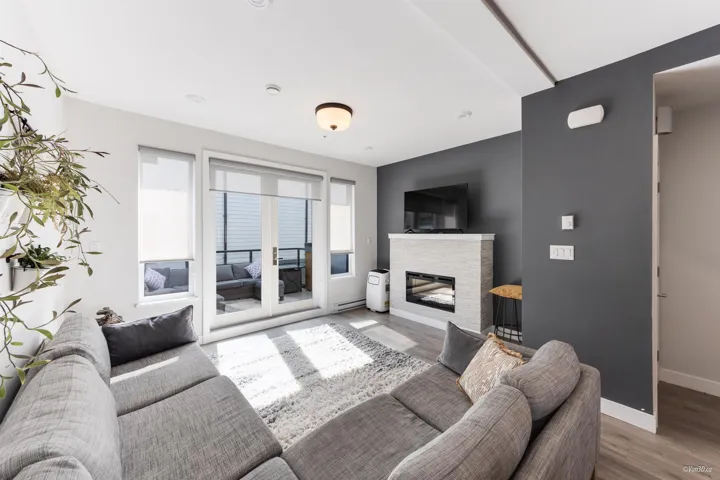 Living room featuring wood finished floors, a stone fireplace, and a baseboard radiator