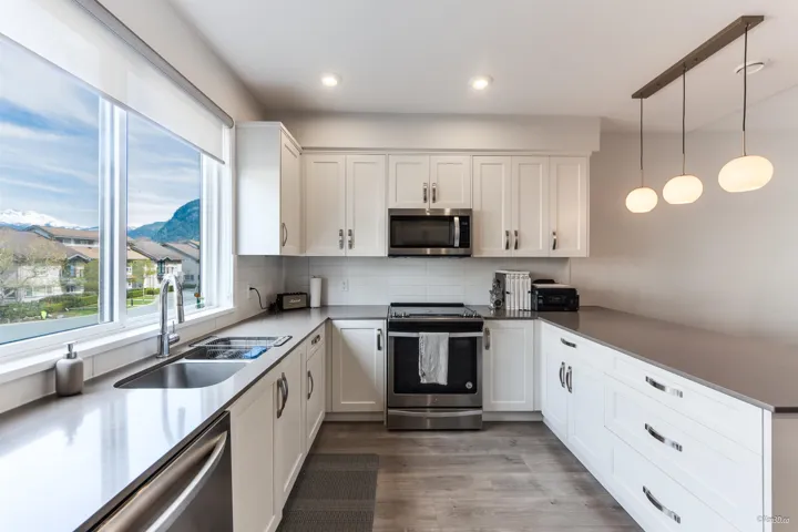 Kitchen with stainless steel appliances, a peninsula, white cabinetry, decorative backsplash, and recessed lighting