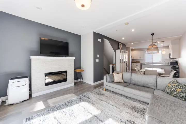 Living room featuring wood finished floors, a stone fireplace, and recessed lighting
