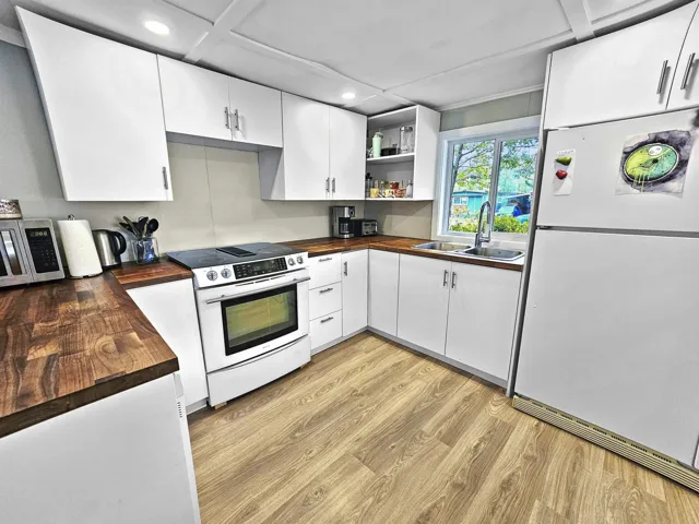 Kitchen featuring butcher block countertops, freestanding refrigerator, a sink, and electric range oven
