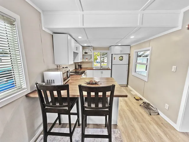 Dining room with light wood-type flooring, baseboards, and recessed lighting